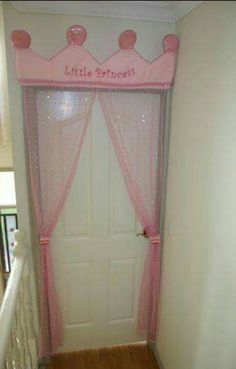 a door with pink curtains and princess crown on it's head is in the hallway