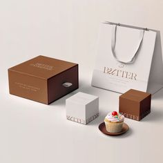 a cupcake sitting on top of a plate next to two boxes and a bag