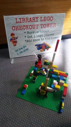 there is a sign that says library lego checkout tower on the carpeted floor