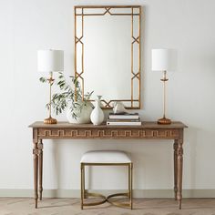 a table with a mirror, lamp and vase on it