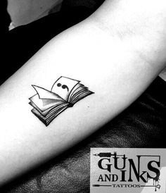 a black and white photo of a book tattoo on the arm