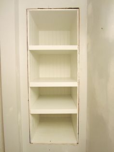 an empty shelf in the corner of a room with white paint on it and no one inside