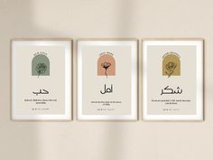 three framed posters on the wall with arabic writing in different colors and shapes, each featuring an image of a flower