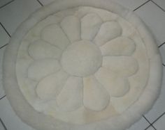 a white rug on the floor with a flower design in it's center piece