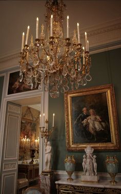 a chandelier hanging from the ceiling in a room with paintings on the walls