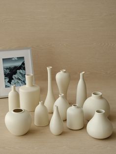 a group of white vases sitting on top of a table next to a framed photo