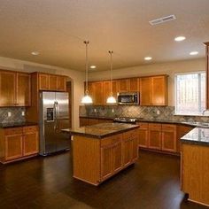 a large kitchen with wooden cabinets and granite counter tops, along with stainless steel appliances