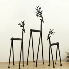 three metal giraffe sculptures sitting on top of a wooden floor