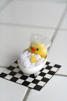 an easter chick in a bathtub on a black and white checkered tile floor