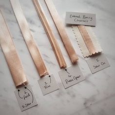 three different types of satin ribbons on a marble counter top with tags attached to them