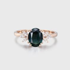 an oval green tourmaline and diamond ring with two white diamonds on the band