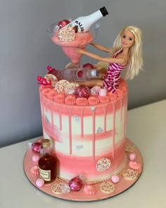 a barbie doll sitting on top of a pink cake with bottles and confetti