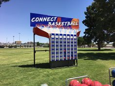 a sign for a basketball game on the grass in front of some red and blue balls