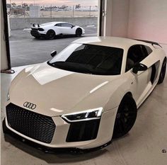 two white sports cars parked in a garage