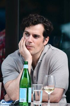 a man is sitting at a table with wine glasses and bottles in front of him