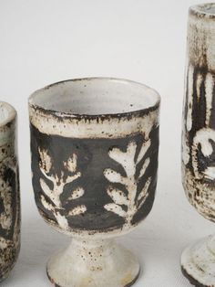 three white and black vases sitting next to each other on top of a table