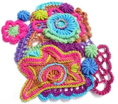 several crocheted items are arranged on a white surface, including a camera and flowers