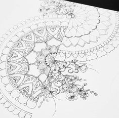 an intricate drawing on paper with flowers and leaves in the center, next to a pen