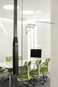 a meeting room with green chairs and a black pole in the middle of the room