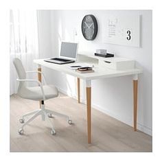 a white desk with a laptop on it and a clock mounted to the wall behind it