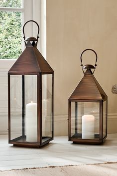 two brown lanterns sitting next to each other on top of a white floor in front of a window