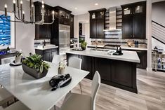 a large kitchen with black cabinets and white counter tops, along with a dining room table