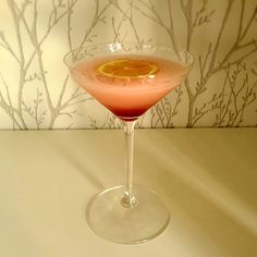 a pink drink with an orange garnish in it