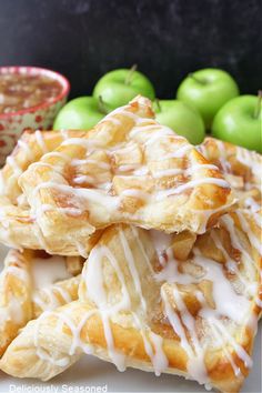 apple cream cheese puff pastries stacked on top of each other with apples in the background