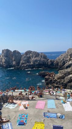 people are lounging on the beach with towels and blankets around them, while others swim in the water