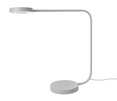 a white table lamp with a round light on the base and a cord attached to it