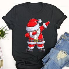 Ugly Christmas T Shirt, Dabbing Santa Claus Christmas Kids Boys Girls Dab Xmas Gifts T Shirt, Christmas Tshirt Designs The T-Shirt, a timeless wardrobe staple, combines comfort with effortless style. Crafted from soft, breathable fabrics, it ensures a cozy fit for everyday wear. Its versatility makes it a go-to choice for various occasions, from casual... American Football Shirt, Christmas Photograph, Dancing Santa, Christmas T Shirt Design, Merry Christmas Happy Holidays, Football Tee, Santa Shirts, Playing Football, Funny Xmas