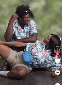 a woman sitting on the ground next to a man who is holding his arm around her