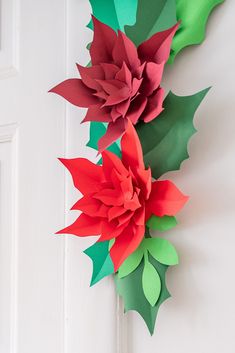 paper flowers are hanging on the wall next to a white door with green and red decorations