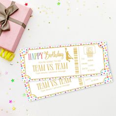 two pink and gold birthday tickets next to a present