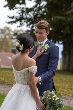 a man in a suit and tie standing next to a woman wearing a wedding dress