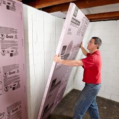 a man holding up a large poster in front of a wall