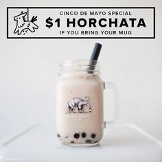 a glass mug filled with milk and chocolate chips on top of a white table next to a sign that says $ 1 horchata if you bring your mug