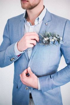 a man in a blue suit adjusts his boutonniere