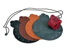 four pieces of leather with holes in the middle and a red bag on one side