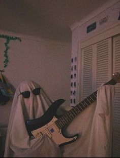 a guitar sitting on top of a bed covered in a blanket next to a closet