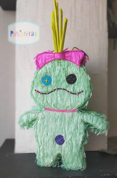 a paper mache monster with pink hair and green body sitting on top of a table