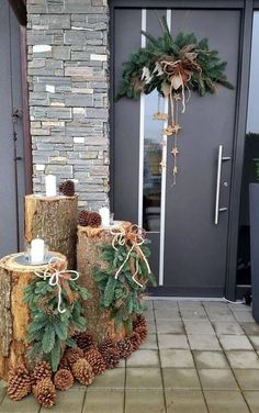 two logs with pine cones and evergreen leaves on them sitting in front of a door