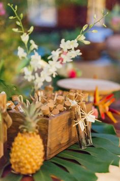 pineapples are placed in wooden crates on a table with other decorations and flowers