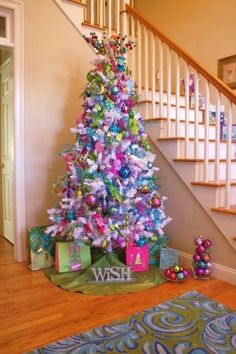 a decorated christmas tree in front of a staircase