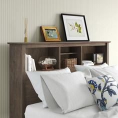 a bed with white sheets and pillows on top of it next to a wooden bookcase