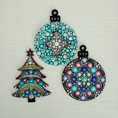 two christmas tree ornaments on a white surface with black and blue circles in the center