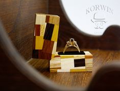 a wooden ring box sitting on top of a wooden table next to a wedding ring