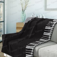 a black and white piano keyboard blanket sitting on top of a couch next to a window