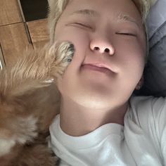 a young boy laying on the floor with his eyes closed next to a small dog