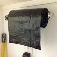 a black towel holder hanging from the side of a wall next to a roll of toilet paper